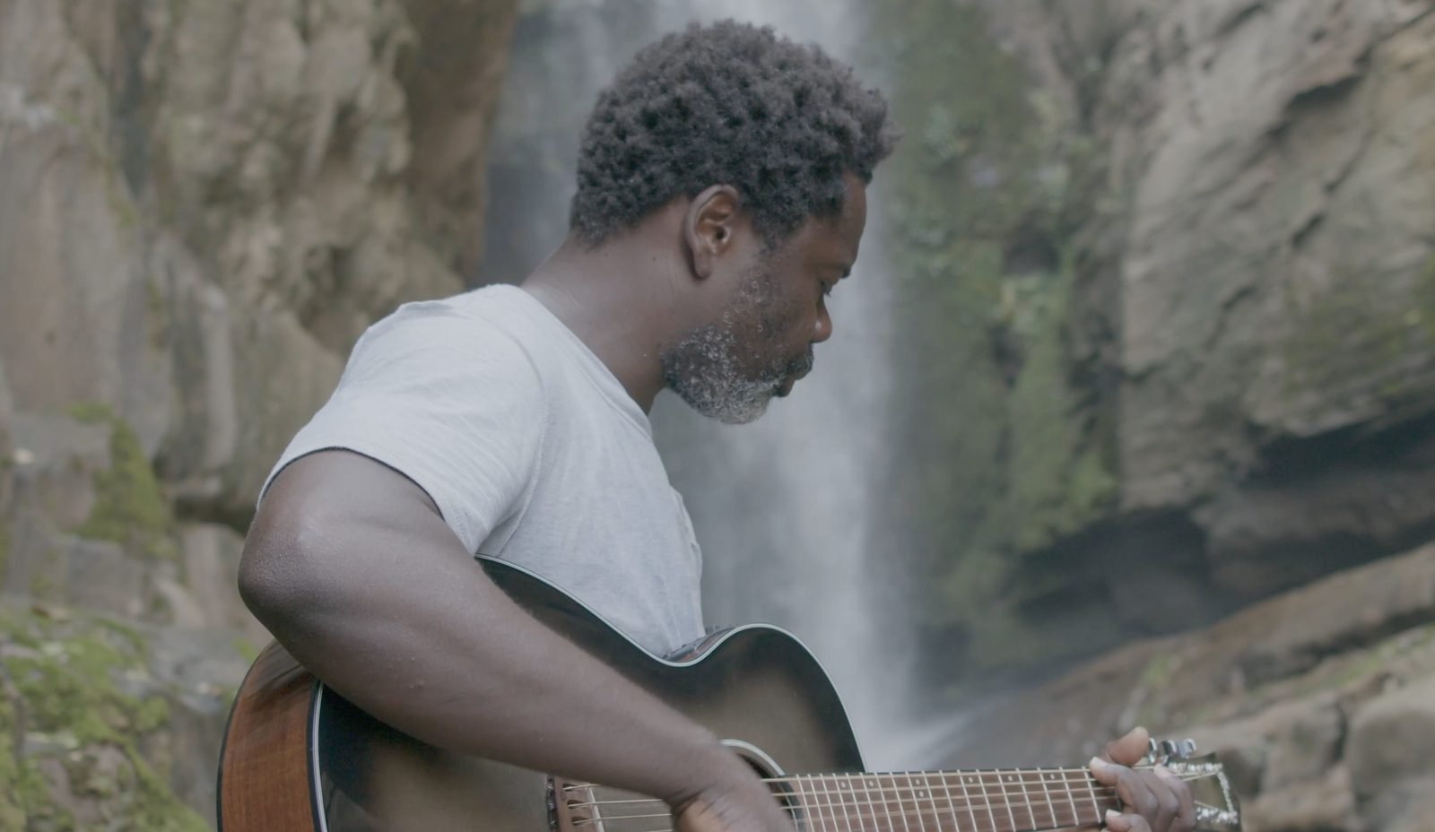 Mermans playing guitar by a waterfall