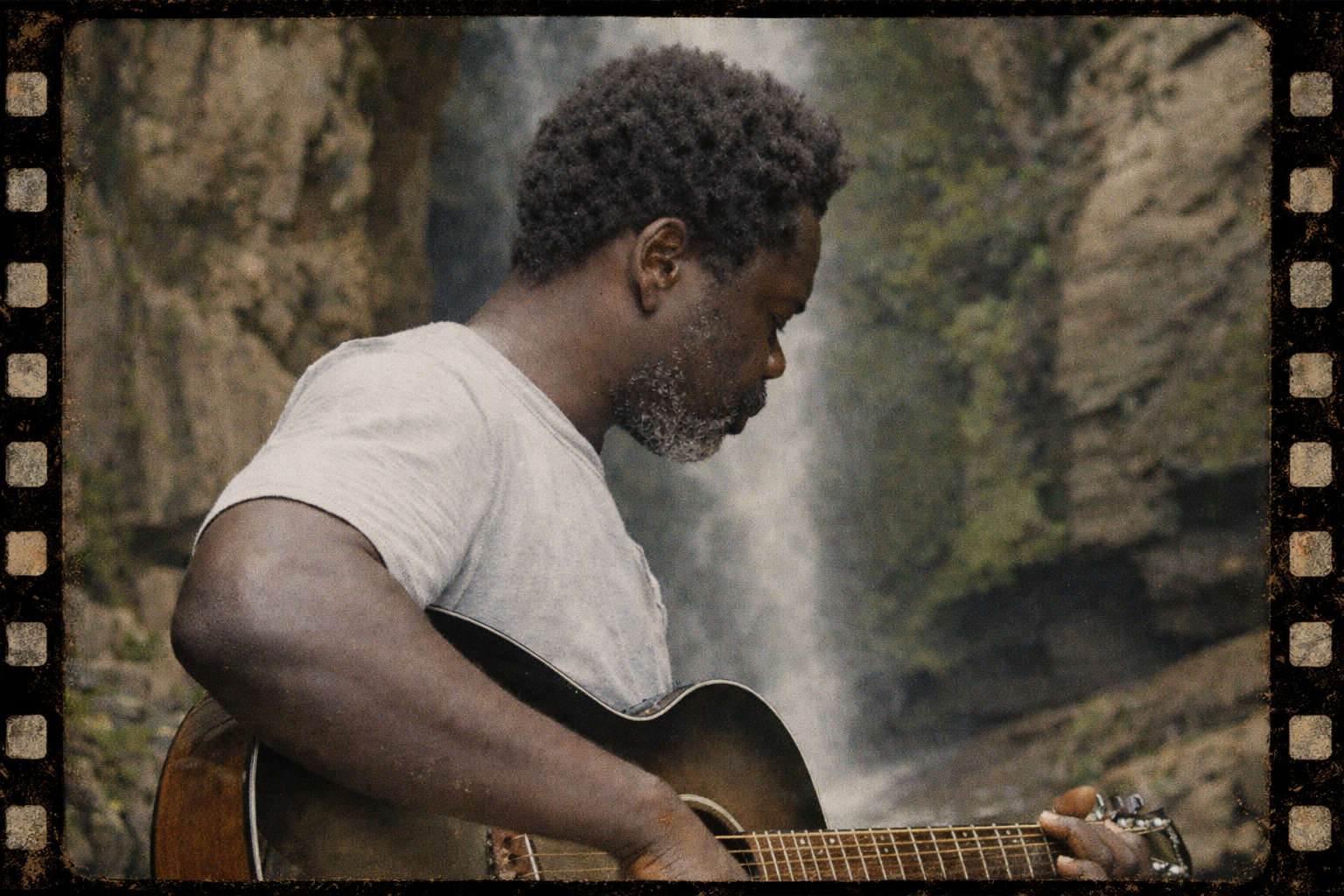 Mofaya playing guitar by waterfall